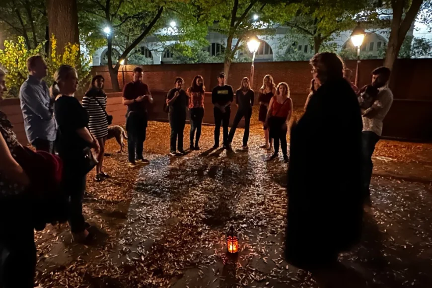Cloaked guide leading a lantern lit night tour group in Lancaster PA