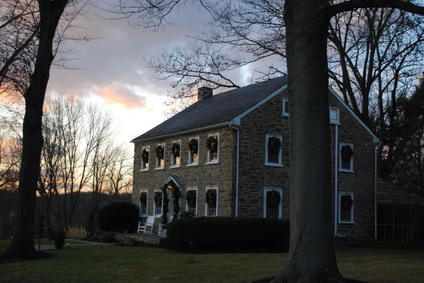 Historic stone farmhouse decorated with holiday wreaths at dusk at Shallowbrook Farm in Lancaster PA