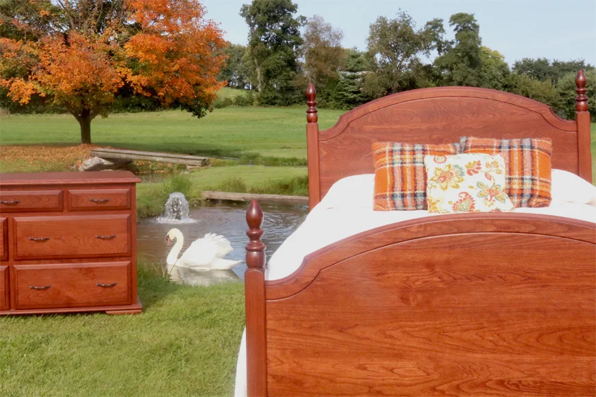 Cherry wood bed and nightstand composited against a pond scene from George's Furniture in Lancaster County PA