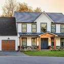Farmhouse style home exterior at dusk with covered front porch built by Eby Exteriors in Lancaster County PA