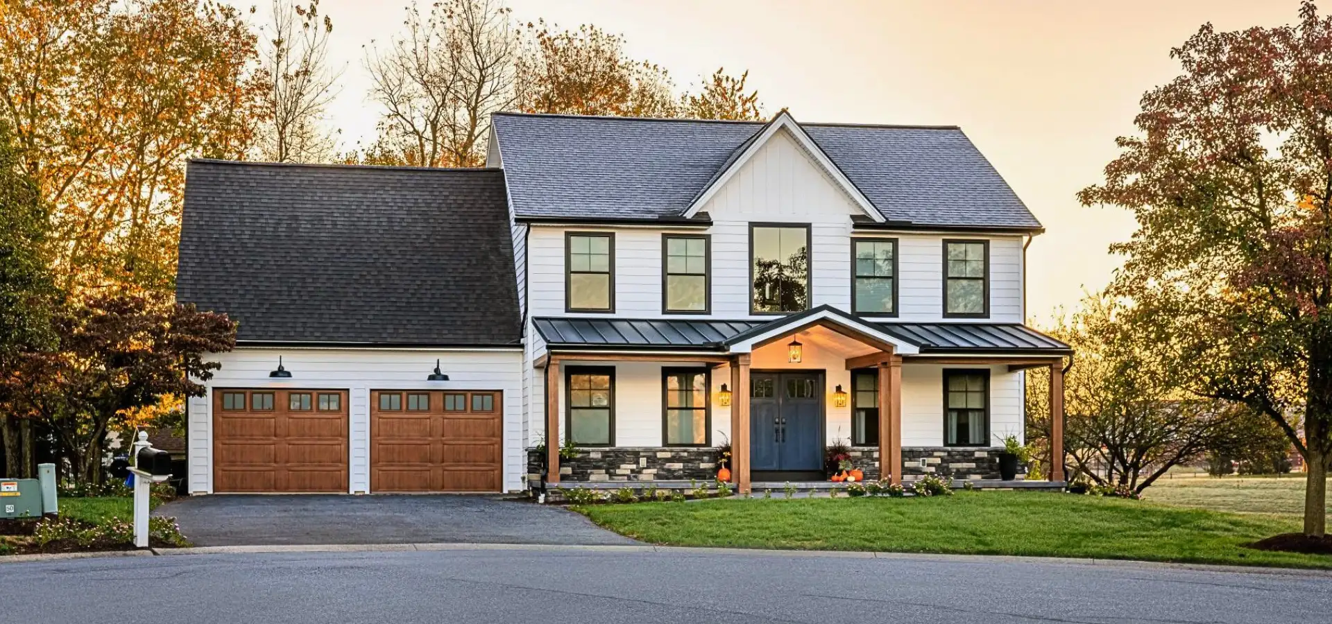 Farmhouse style home exterior at dusk with covered front porch built by Eby Exteriors in Lancaster County PA