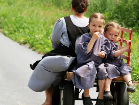Amish children riding on a wagon along a country road, home page hero image for LancasterPA.com