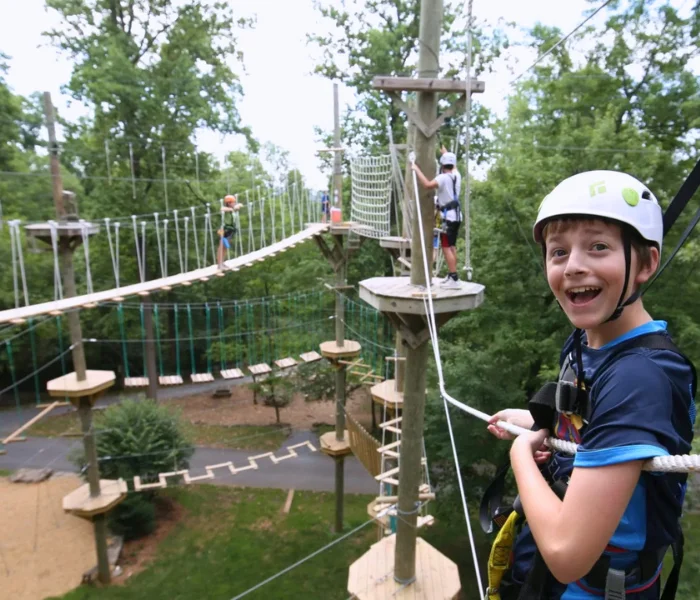 Child in a safety helmet and harness on an aerial ropes course, home page hero image for LancasterPA.com coupons