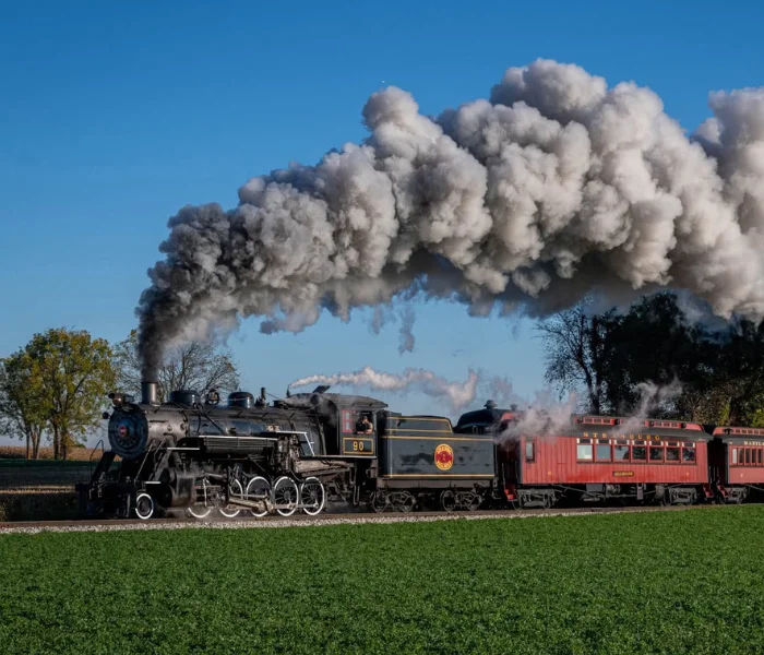 Steam locomotive pulling passenger cars with heavy smoke overhead at Strasburg Rail Road, home page hero image for LancasterPA.com