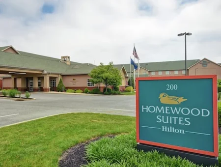 Homewood Suites by Hilton exterior in Lancaster, PA, with the entrance sign, American and hotel flags, and landscaped grounds