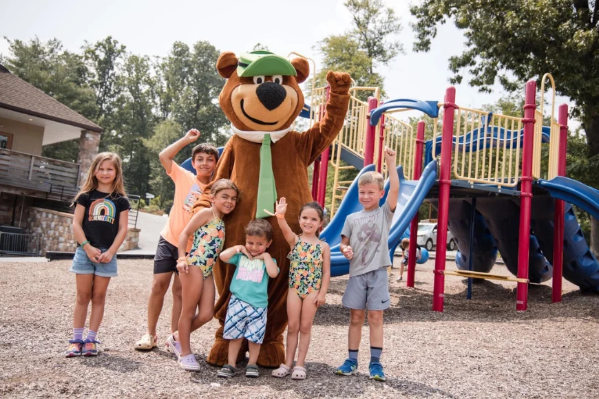 Kids posing with Yogi Bear mascot at playground at Jellystone Park Quarryville in Lancaster PA