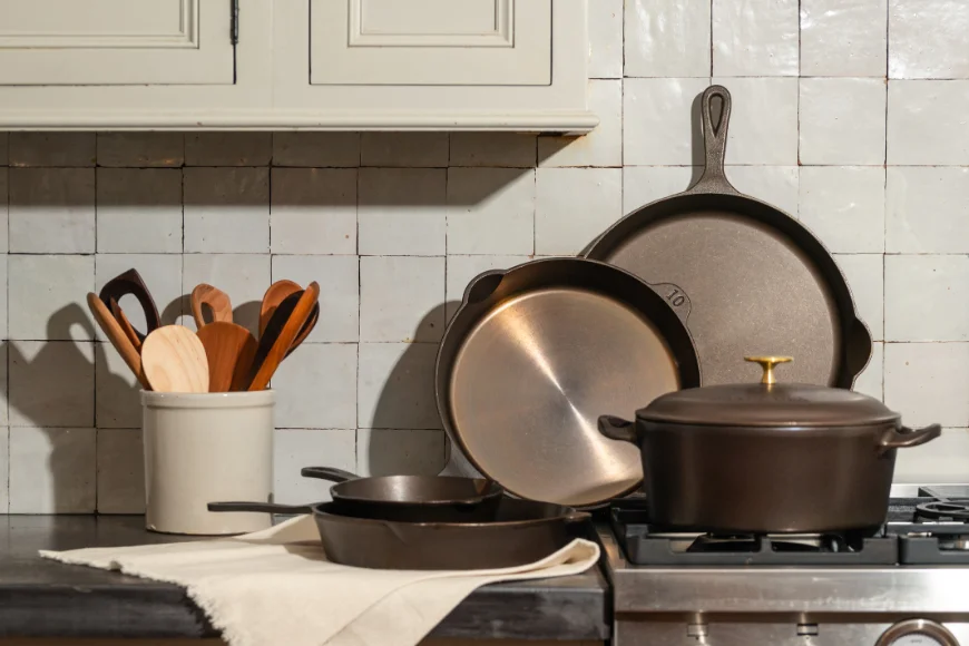Alt text: Cast iron skillets, Dutch oven, and wooden utensils displayed on a stovetop