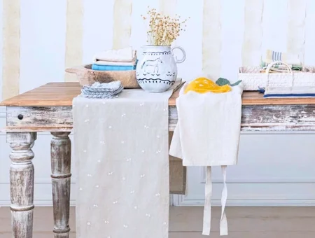 Distressed farmhouse table styled with linen runner, ceramic pitcher, and folded towels