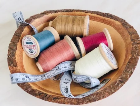 Spools of thread and measuring tape displayed in a wooden bowl