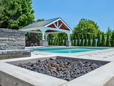 Poolside pavilion with fire pit and stone landscaping by Clymer's Landscaping in Lancaster PA