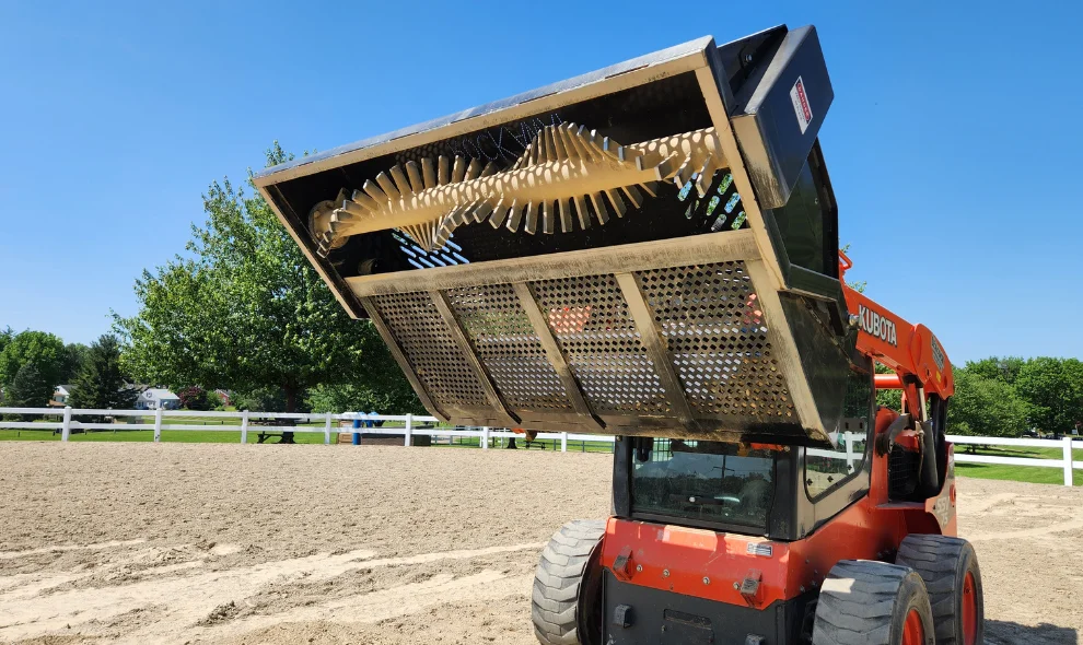 Kubota skid steer with rock grapple bucket raised in riding arena, Lancaster PA farm equipment