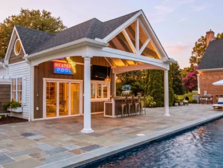 Pool house with covered patio, illuminated pool sign, and bar seating beside pool at dusk, Lancaster PA outdoor structures