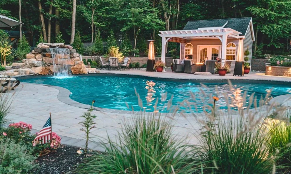 Backyard pool with stone waterfall and pergola-covered shed lounge area, Lancaster County PA sheds