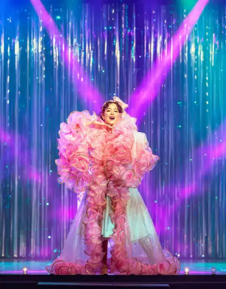 Jukebox Generation solo performer in ruffled pink costume under stage lights at Magic and Wonder Dinner Theater in Lancaster PA