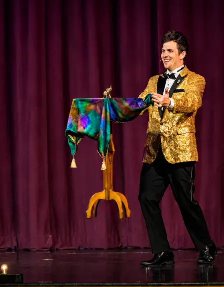 Magic and Wonder Dinner Theater magician in gold jacket performing floating table trick in Paradise PA