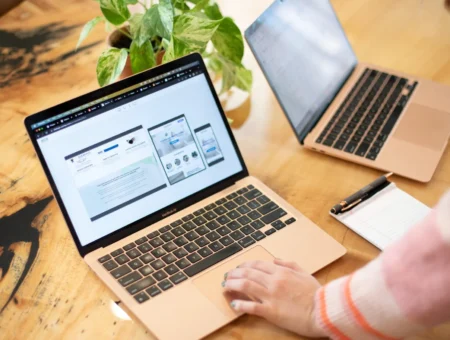 Person browsing responsive website design on laptop screen at wood desk