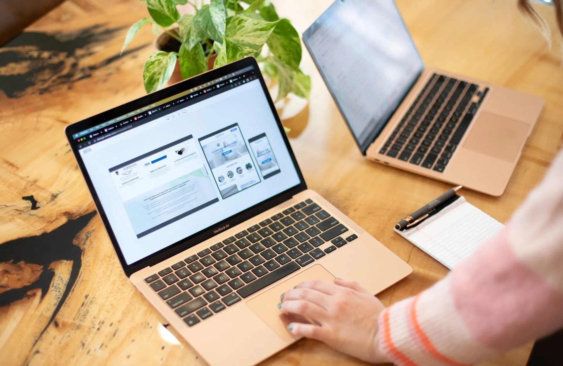 Person browsing responsive website design on laptop screen at wood desk