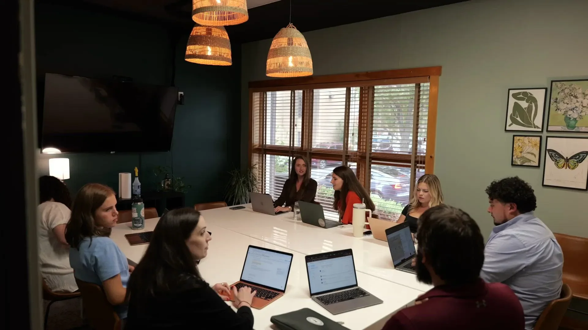 Oostas Marketing team meeting around table with laptops, gallery wall in background, Lancaster PA web design