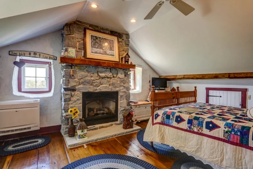 Bedroom with stone fireplace and quilted bed at Osceola Mill House Bed and Breakfast near Intercourse PA