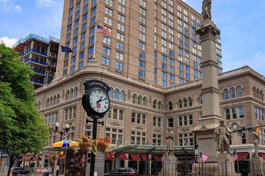 Lancaster PA clock tower on street corner with historic building and monument, Our Town Management