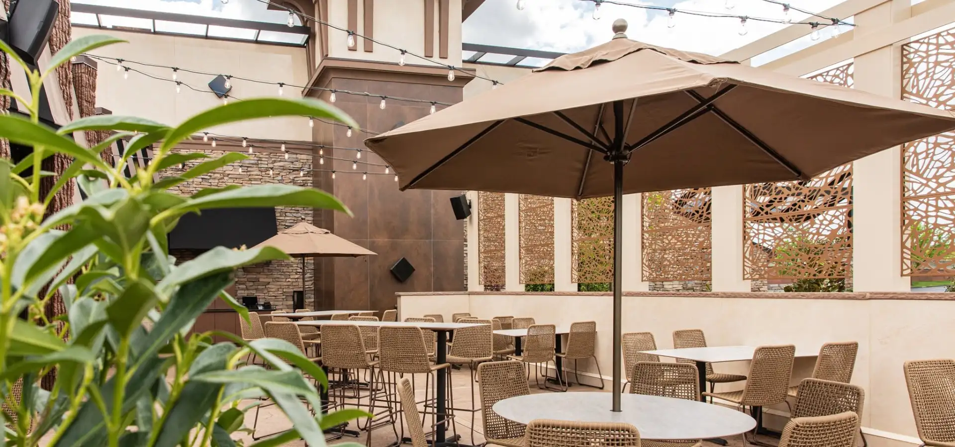 Covered patio dining area at a bistro in Lancaster, PA, with string lights, wicker chairs, umbrella-shaded tables, and decorative screen panels