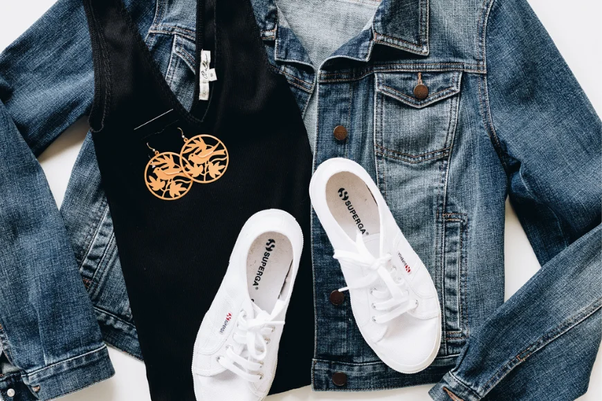 Purple Turtle Consignment Boutique flat lay of denim jacket, black top, earrings, and white sneakers, Lancaster PA resale fashion