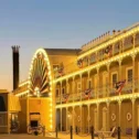 Steamboat-themed hotel exterior on Route 30 East, with wraparound decorative railings, string lights, patriotic bunting, and a large steamboat wheel accent along the facade