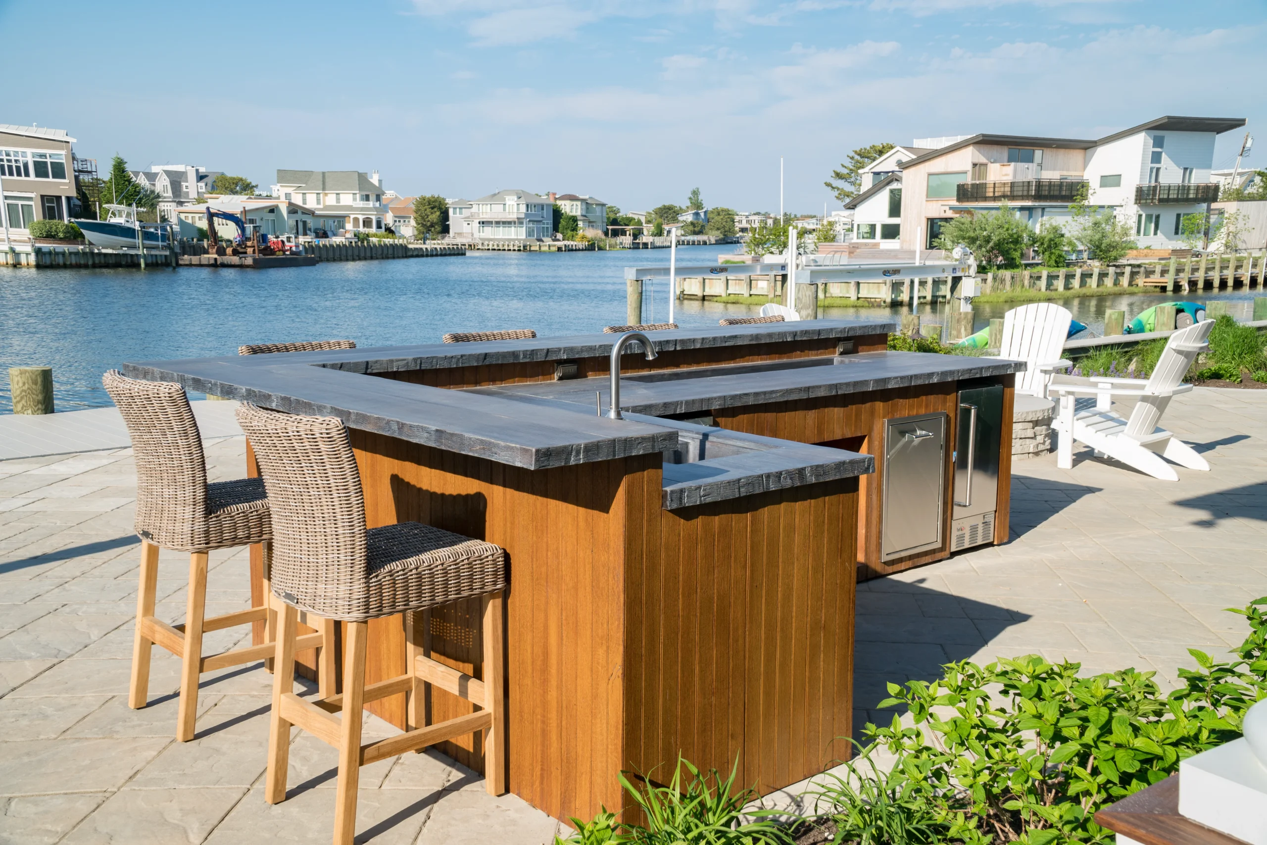 Outdoor kitchen and bar with waterfront view featuring hardscape materials from Sauders Hardscape Supply