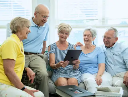 Landis Communities senior residents laughing together on couch with tablet in Lancaster PA