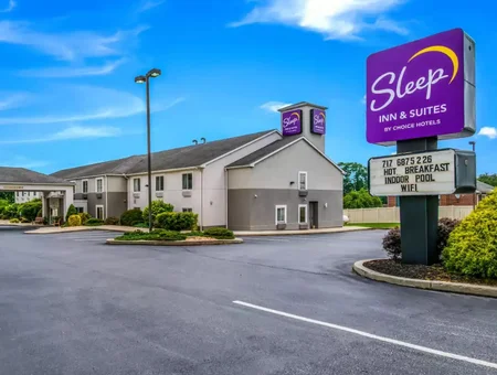 Sleep Inn and Suites exterior sign and building in Lancaster, PA, along the parking lot under a clear blue sky