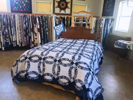 Smucker's Quilts double wedding ring quilt on a bed with quilts displayed on racks, Lancaster County Amish quilt shop