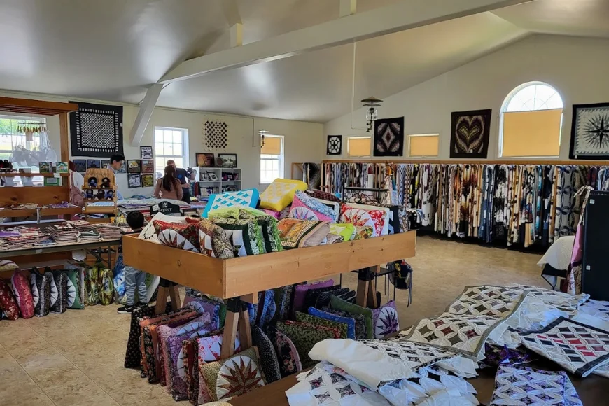 Smucker's Quilts interior with hanging quilts, folded stacks, and shoppers browsing, Lancaster County Amish quilt shop