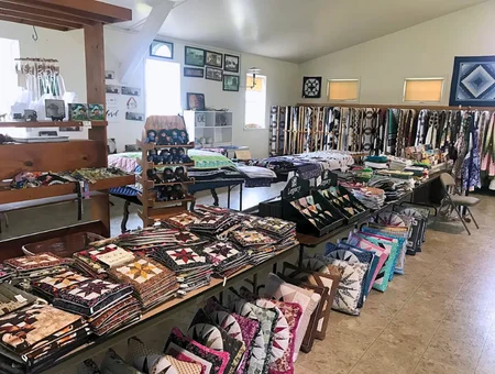 Smucker's Quilts folded quilts, pillows, and fabric bolts displayed in shop, Lancaster County Amish quilt shop