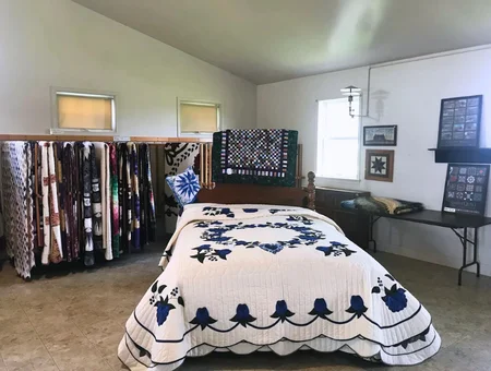 Smucker's Quilts white and navy floral bedspread with quilts on display racks, Lancaster County Amish quilt shop
