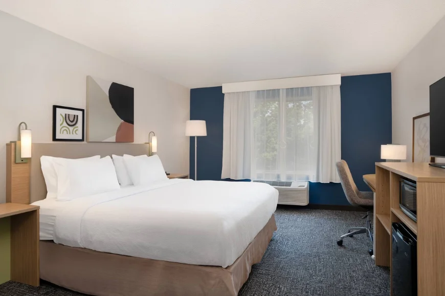 Guest room at Spark by Hilton in Lancaster, PA, with a king bed, navy accent wall, work desk, and modern artwork above the headboard