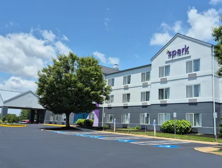Spark by Hilton hotel exterior in Lancaster, PA, with the illuminated rooftop sign, gray and white facade, and a tree-lined parking lot in front