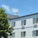 Spark by Hilton hotel exterior in Lancaster, PA, with the illuminated rooftop sign, white multi-story facade, and mature trees along the front of the building