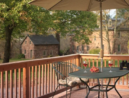 Speedwell Forge B&B deck image: outdoor patio table with wine glasses overlooking the stone forge building and grounds in Lancaster, PA