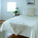 Bedroom with white bedding and floor lamp at Carriage House at Strasburg in Strasburg PA