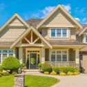 Two-story craftsman-style home exterior in suburban Lancaster, PA, with stone accents, a covered front porch, attached two-car garage, and manicured landscaping