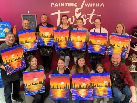 Painting with a Twist group holding finished sunset paintings at Lancaster PA team building event