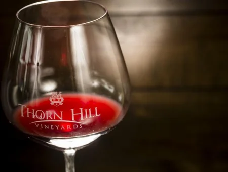 Wine glass etched with Thorn Hill Vineyards logo filled with red wine