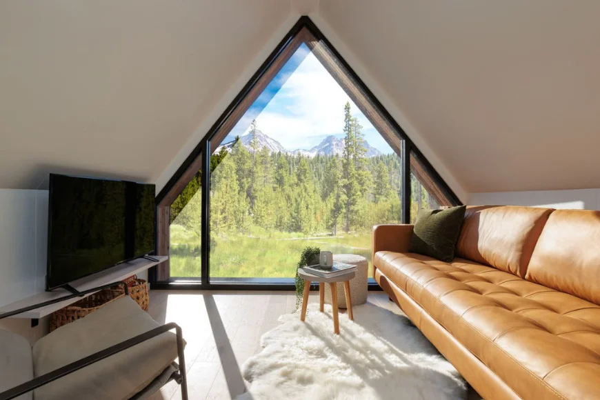 A frame cabin interior with leather sofa and floor to ceiling window overlooking mountains from Zook Cabins
