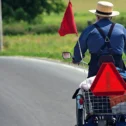 Amish man riding motorized cart with slow moving vehicle sign in Lancaster County, Pennsylvania